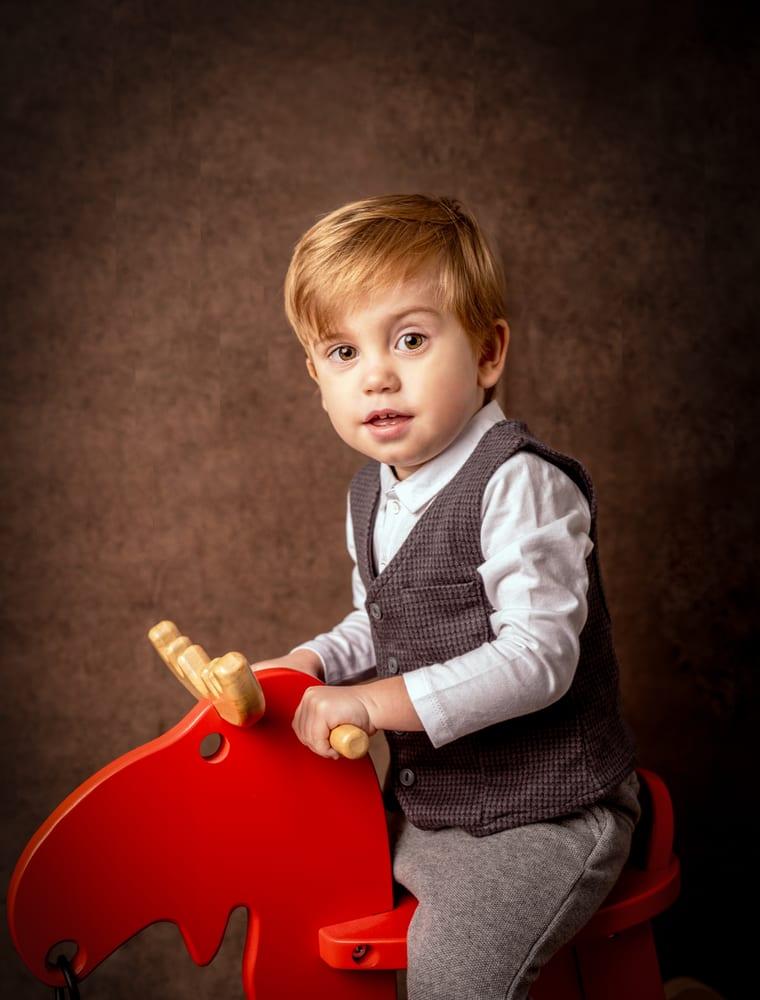 Enfant sur un cheval à bascule rouge en studio